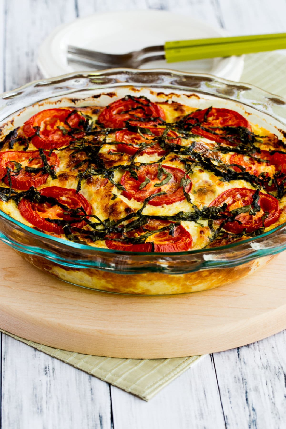 Crustless Three-Cheese Tomato-Basil Quiche shown in baking dish on cutting board