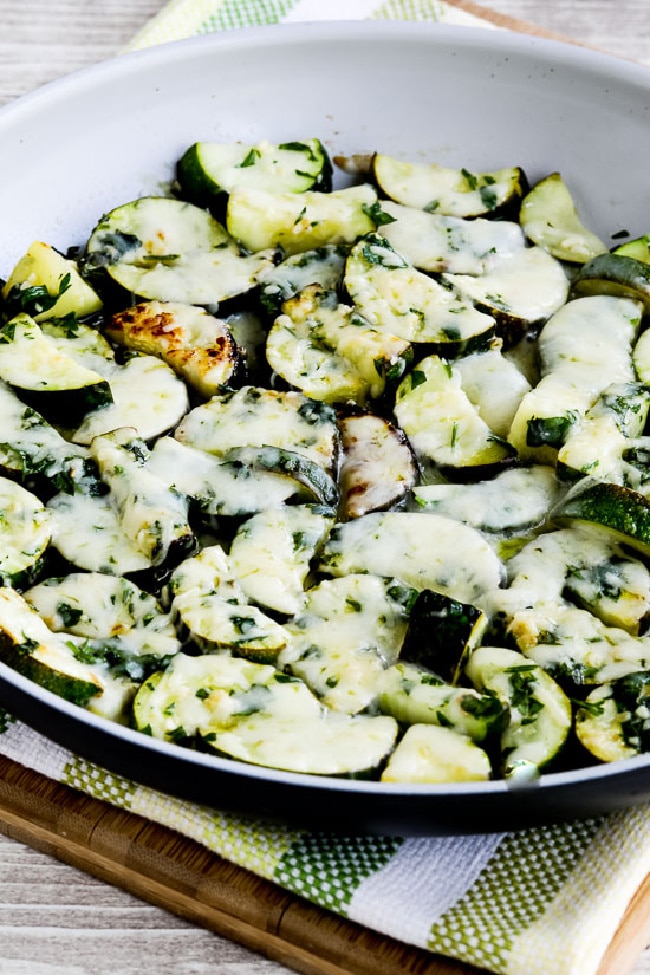 Cheesy Zucchini with Garlic and Parsley shown in pan on cutting board