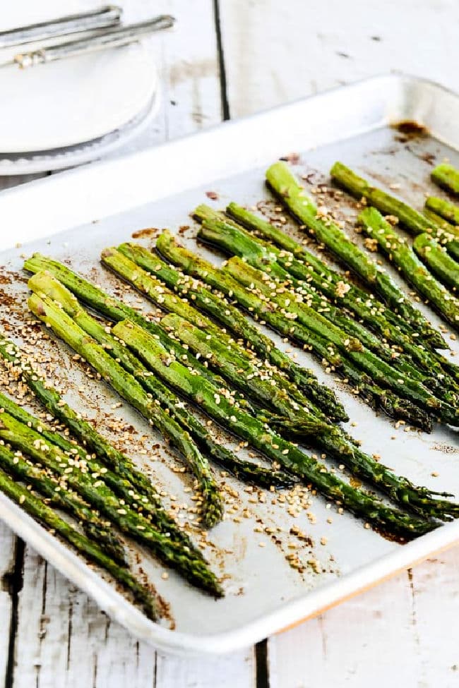 Asparagus with Soy-Sesame Glaze shown on roasting pan with plates in back.
