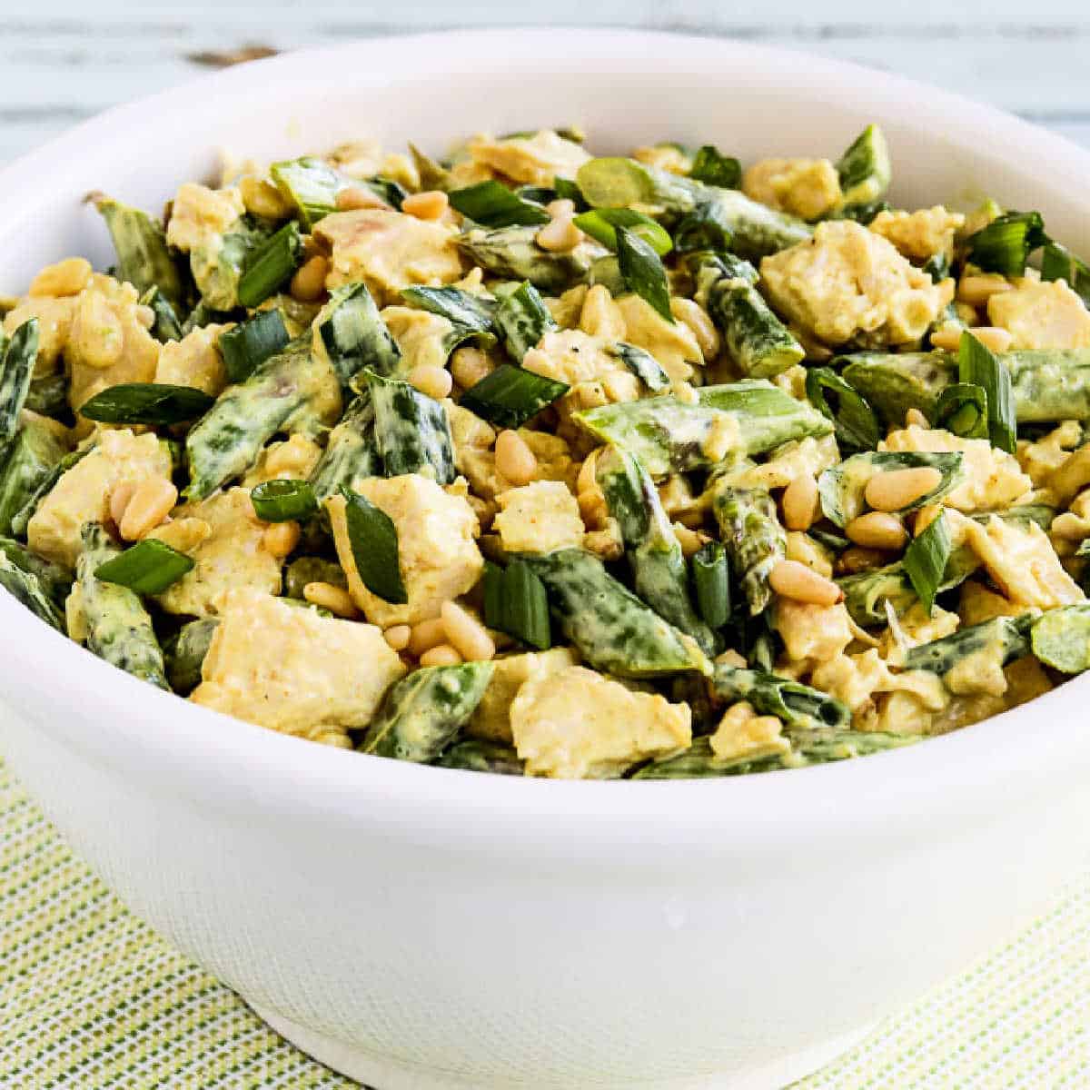 Square image for Curried Chicken Salad with Asparagus and Pine Nuts shown in white bowl.