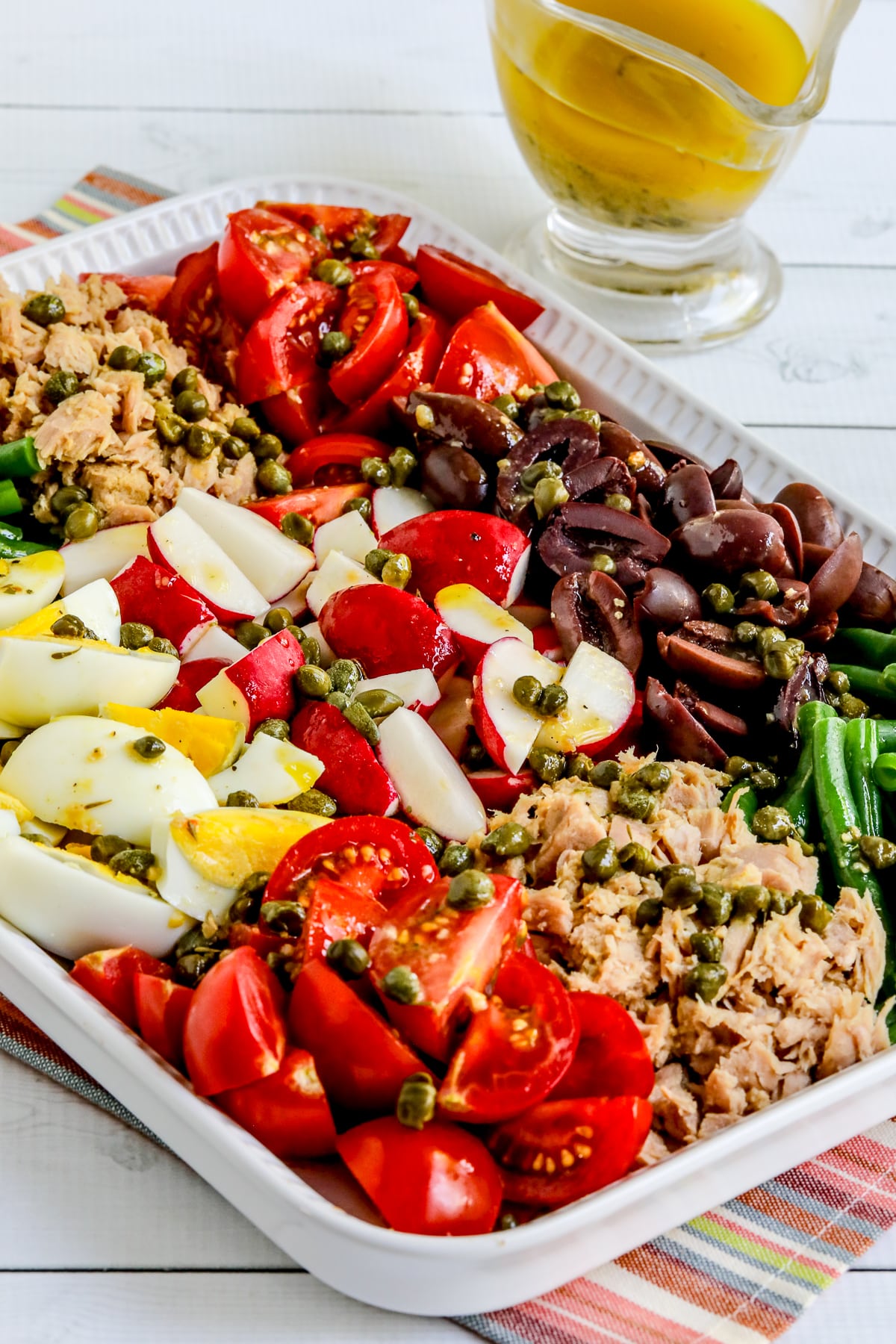 Nicoise Tuna Salad shown on platter with dressing in back.